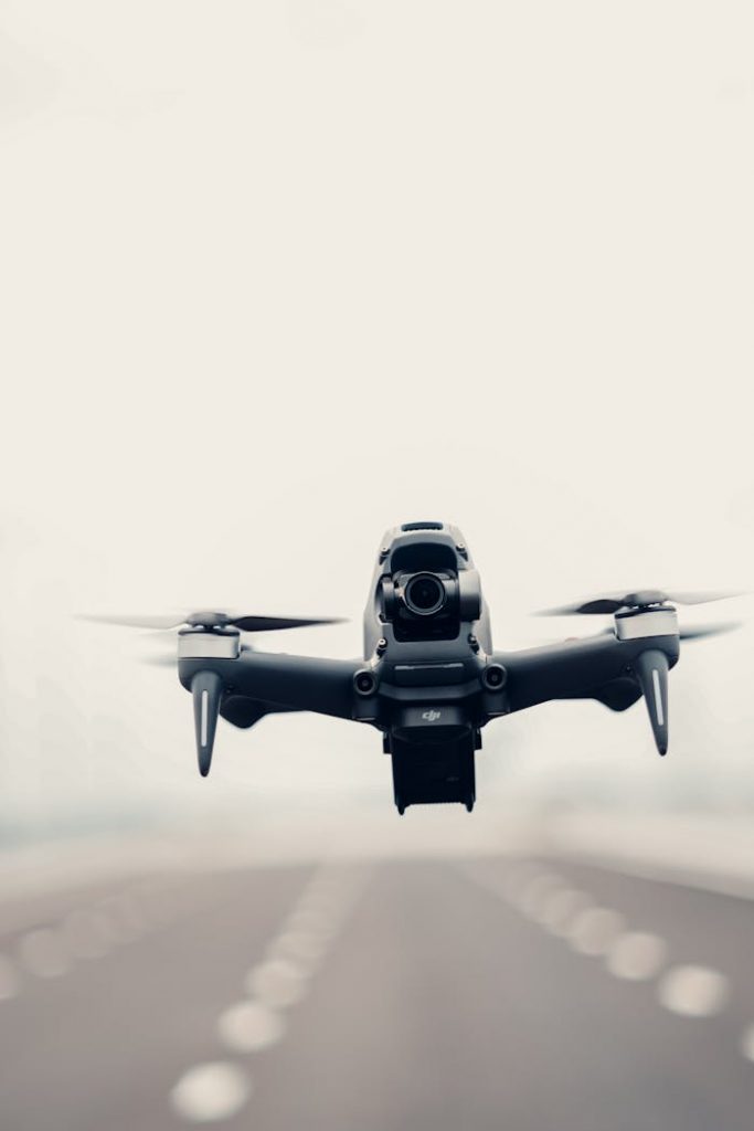 Close-up of a modern drone hovering over an empty road, emphasizing technology and innovation.