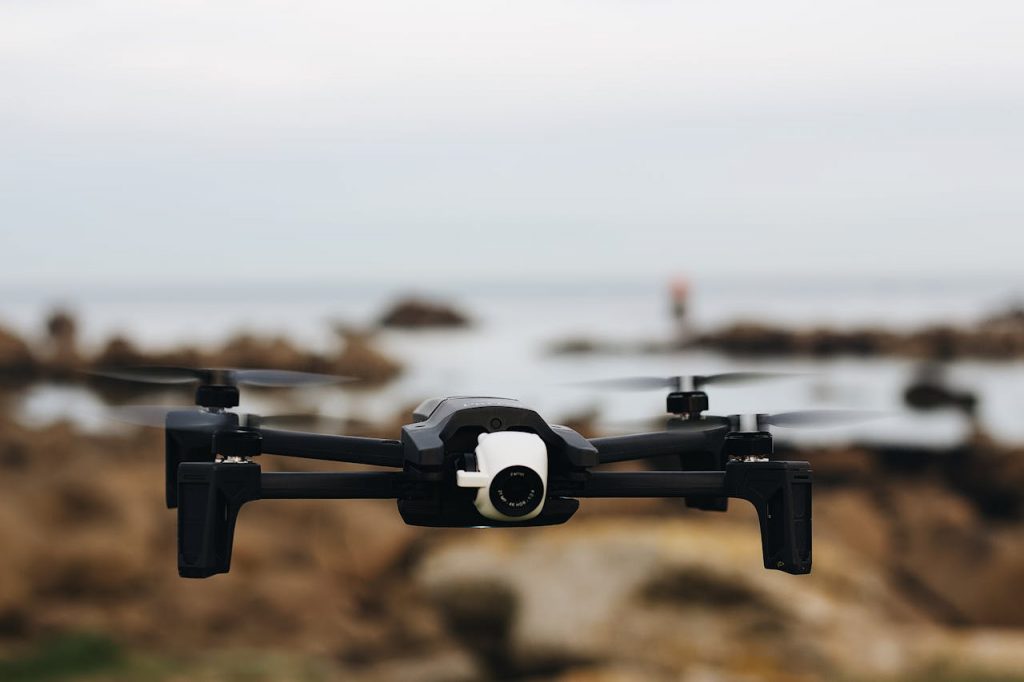 A modern drone flying over a rocky coastline, capturing scenic views.